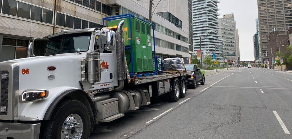 Flatbed truck with transformer and cable.